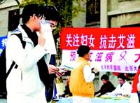 衛生人員到大學校宣傳愛滋病知識和安全性行為；北大和清華反應不佳，大學女生半遮臉羞澀地走過宣傳台。 翻攝自北京青年報 